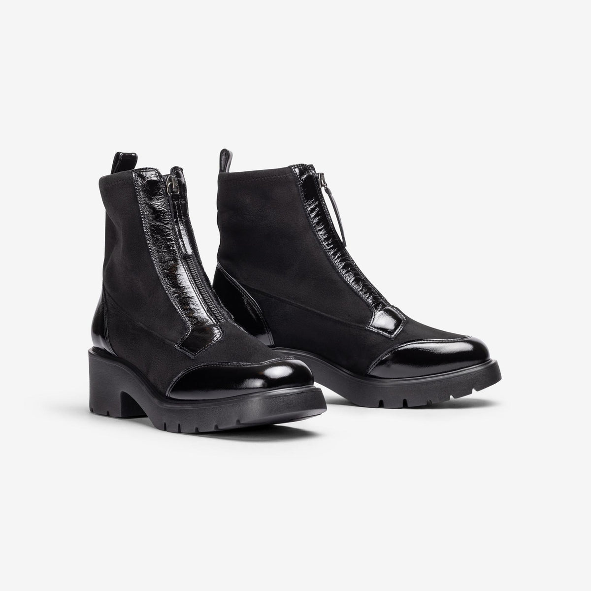 Pair of Unisa Jandro black stretch and patent zip ankle boots with chunky treaded soles, angled view