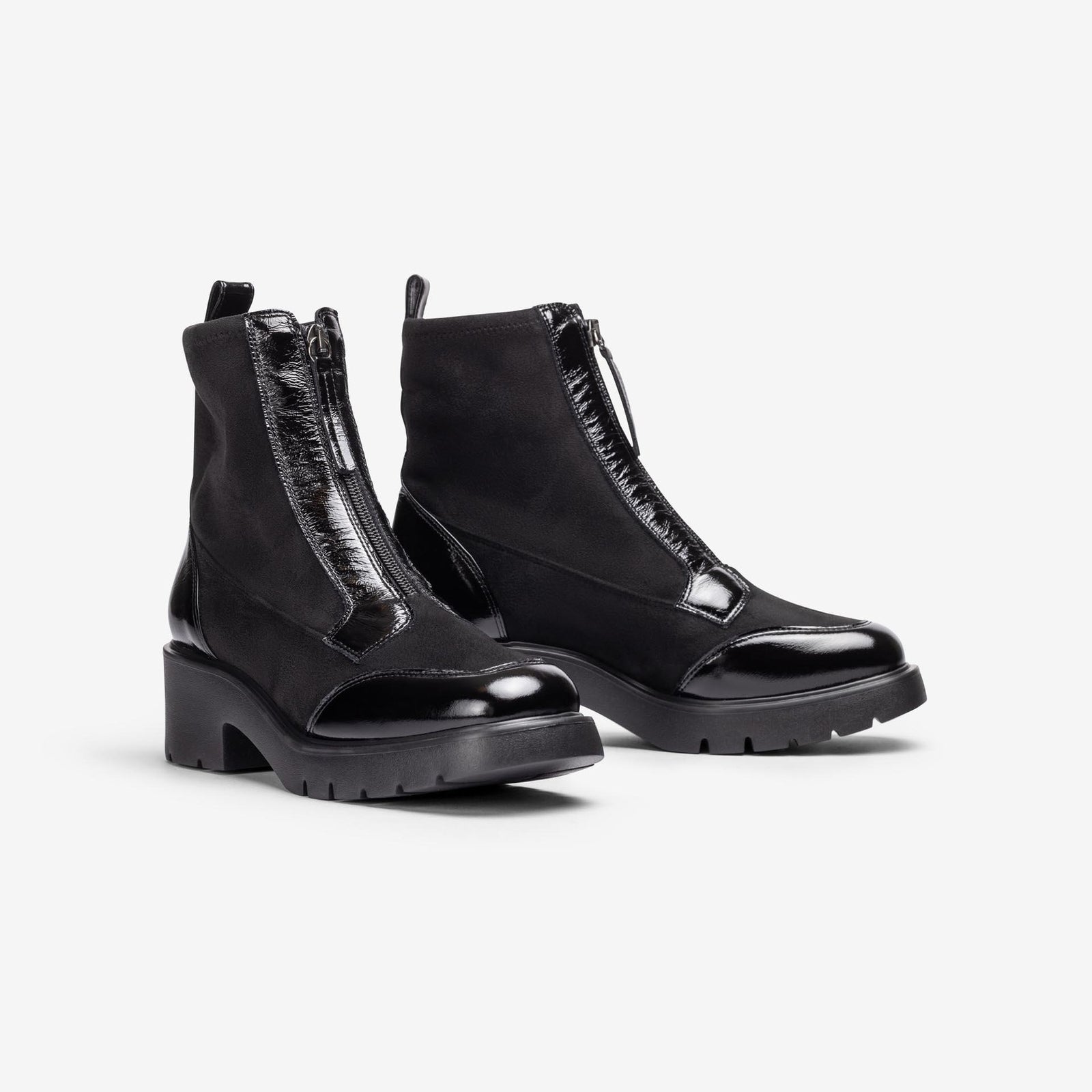 Pair of Unisa Jandro black stretch and patent zip ankle boots with chunky treaded soles, angled view