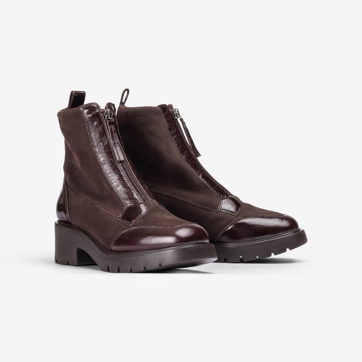 Pair of Unisa Jandro dark brown stretch and patent zip ankle boots with chunky treaded soles, angled view