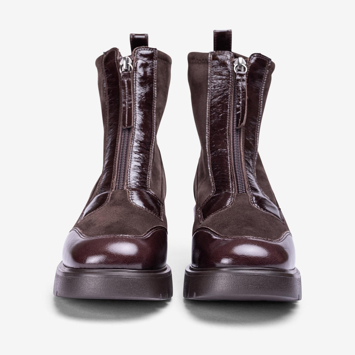 Front view of Unisa Jandro dark brown ankle boots showing front zips, glossy patent toe caps and platform soles