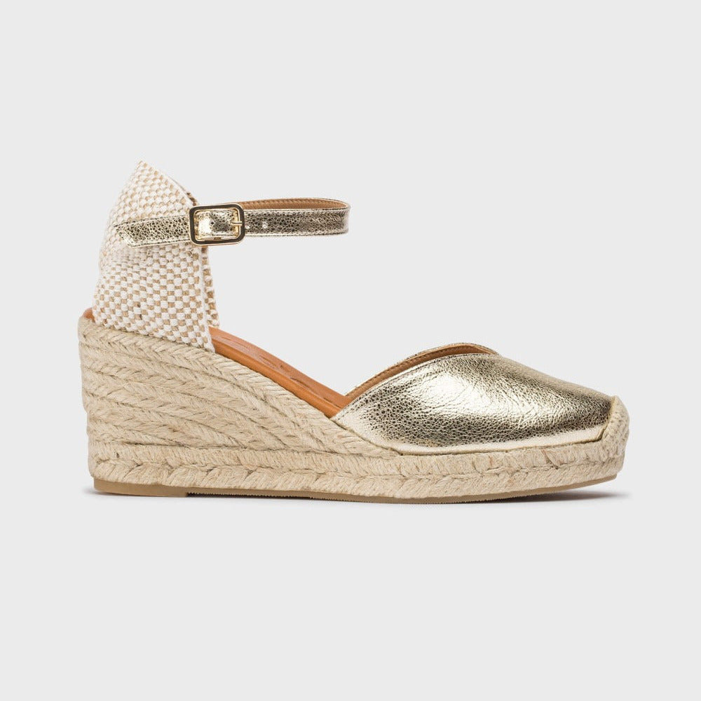 Gold wedge sandal with textured strap on a white background