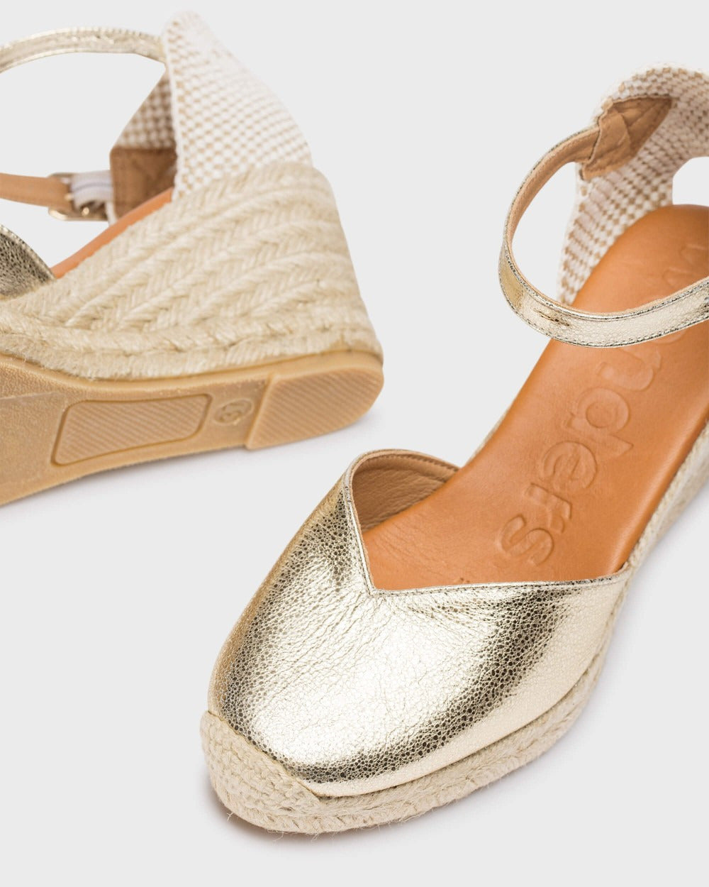 Gold wedge sandals with jute sole on a light gray background